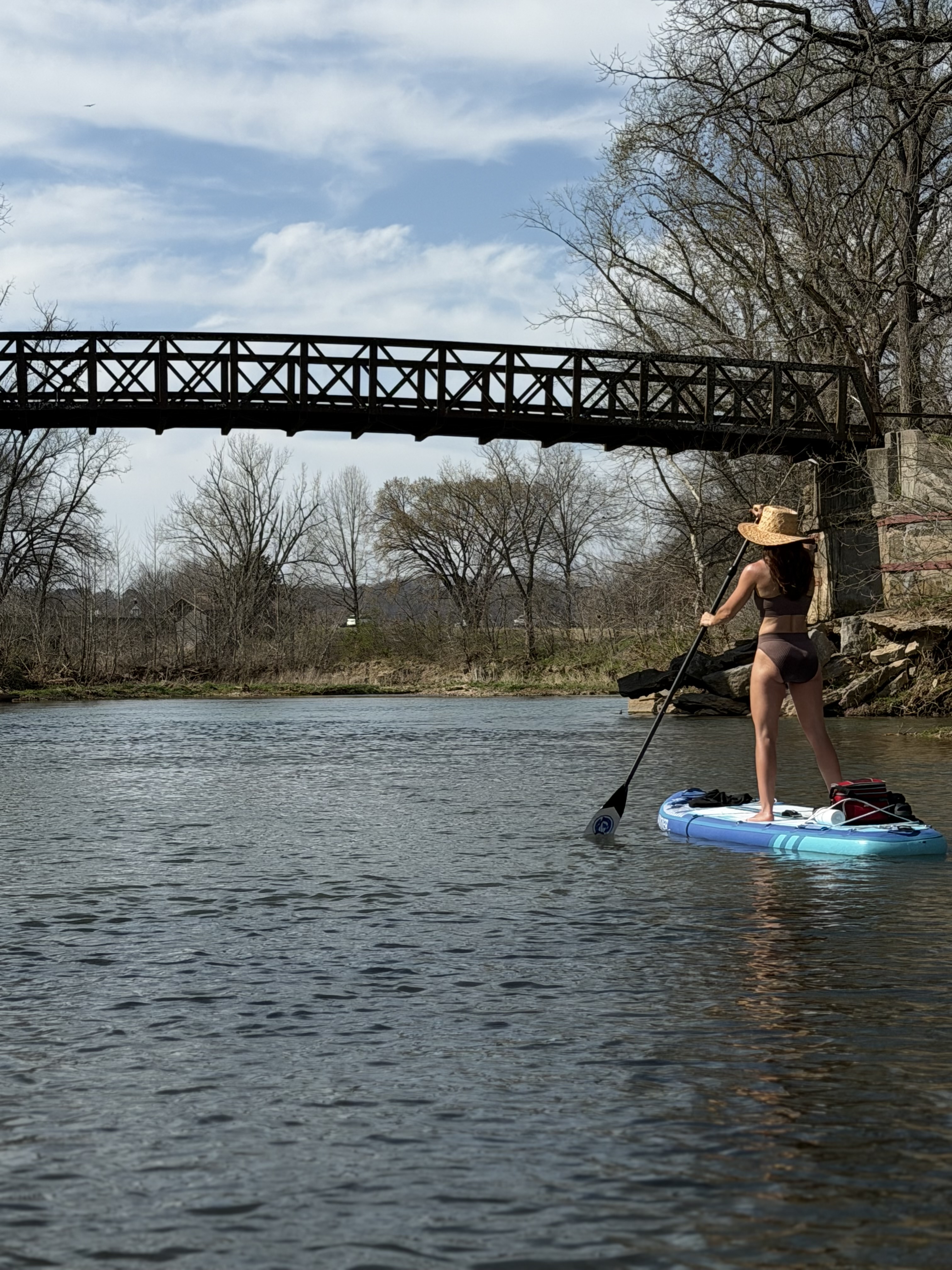 A paddler standing on a SUP board under a bridge on Little Sugar Creek